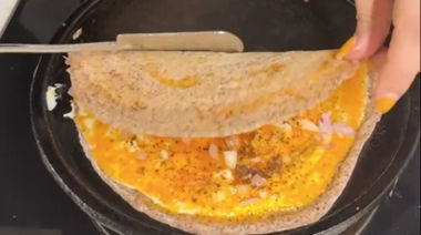 Crispy ghee karam onion egg dosa topped with onions and podi